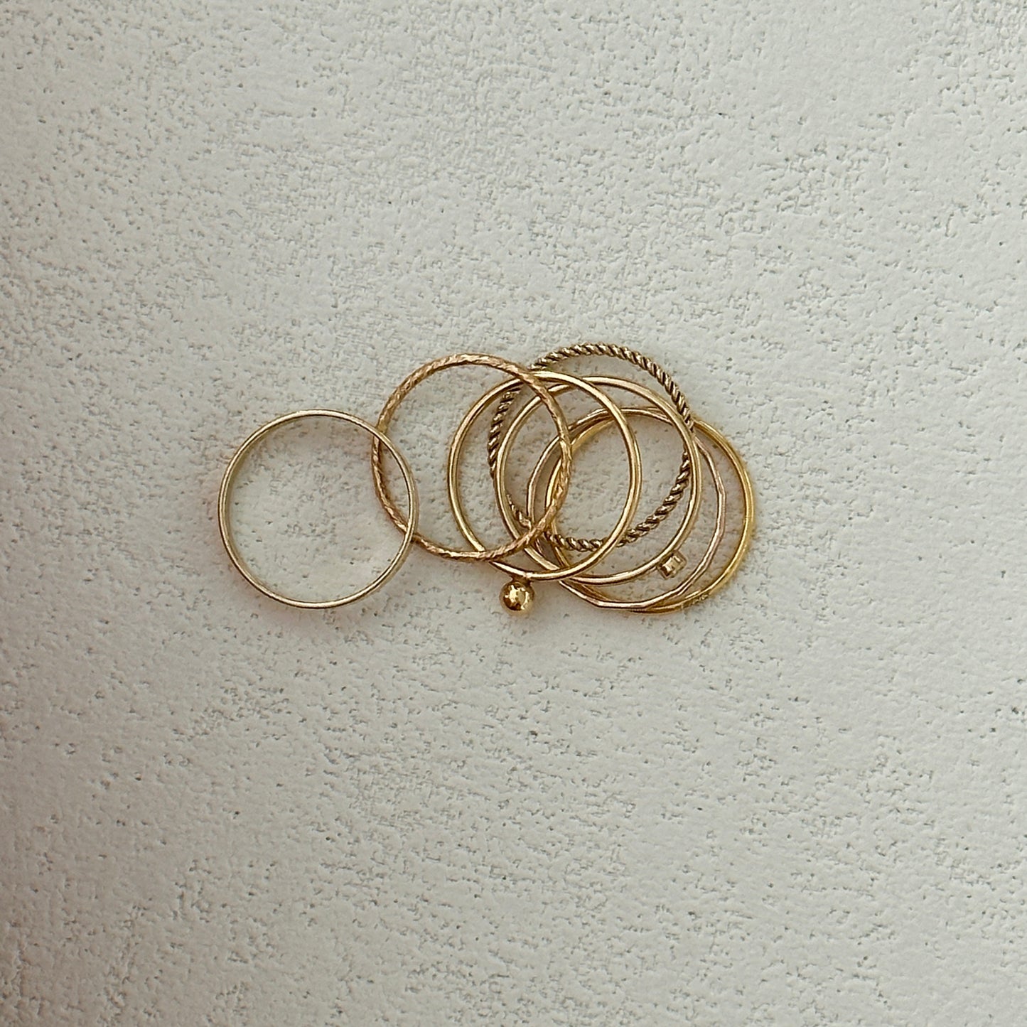 Versatile gold rings with smooth and textured designs stacked on finger