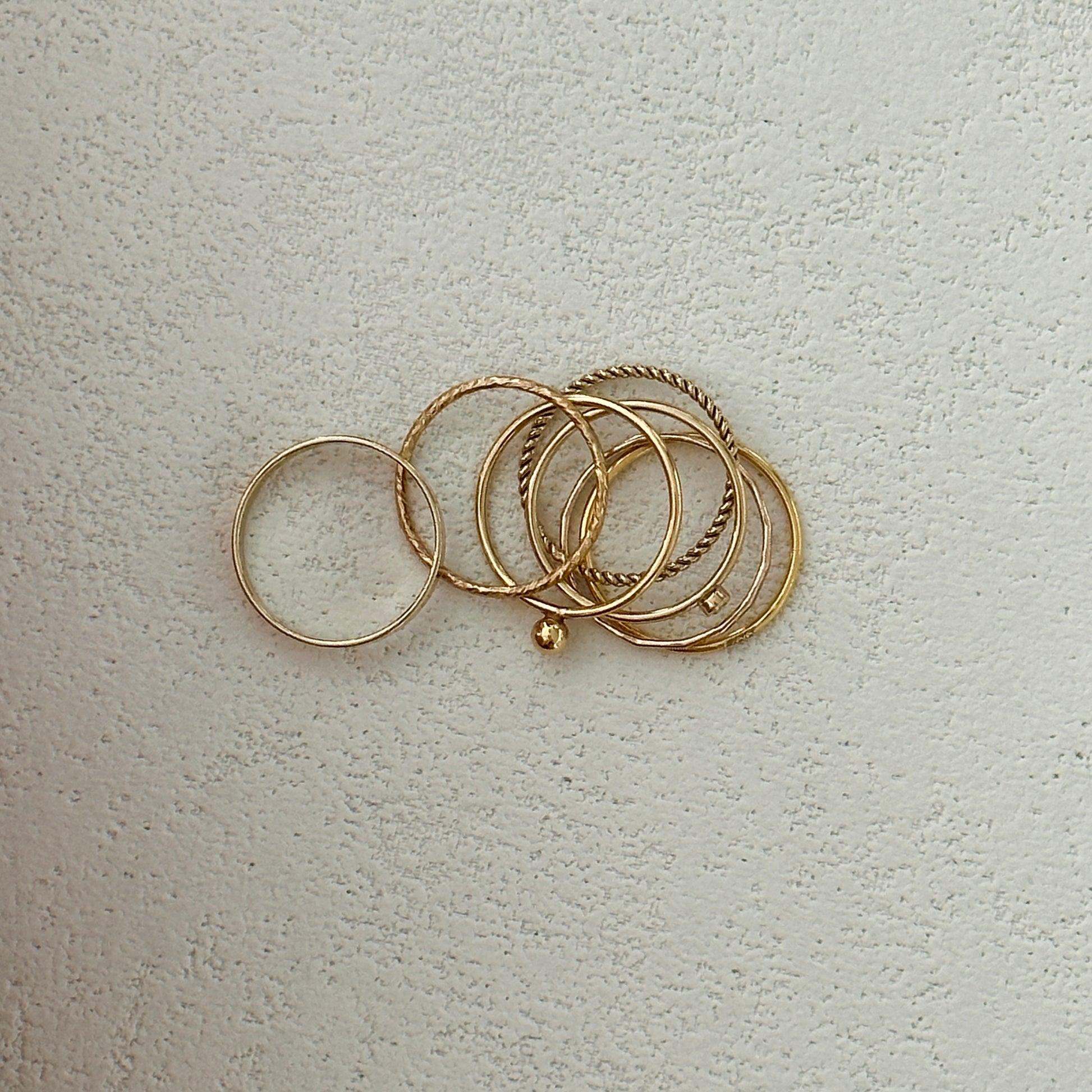 Versatile gold rings with smooth and textured designs stacked on finger